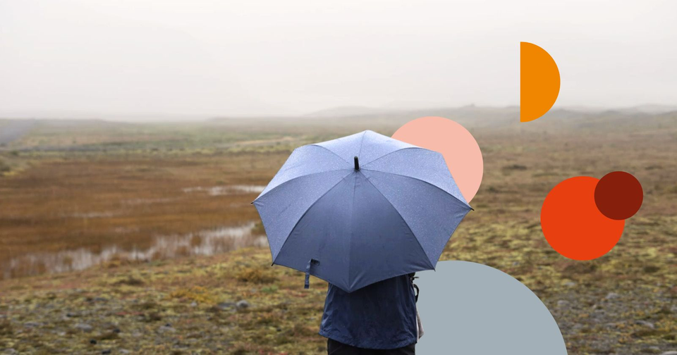 Person med paraply i regn på en slätt